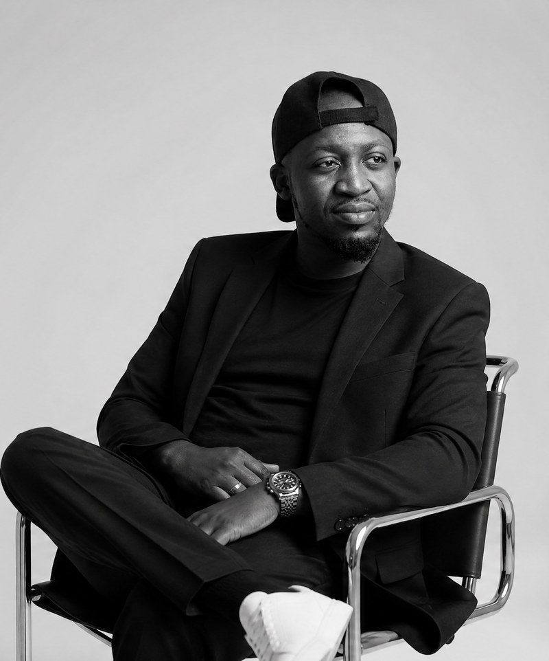Micheal Muleba seated in a black blazer and cap